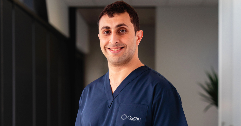 Dr Mark, a Qscan radiologist, in Qscan navy scrubs smiling to camera. 