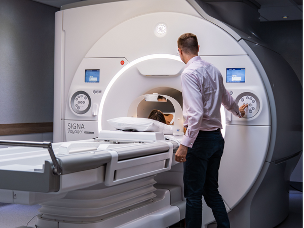 Radiologist operating MRI machine with patient lying down.