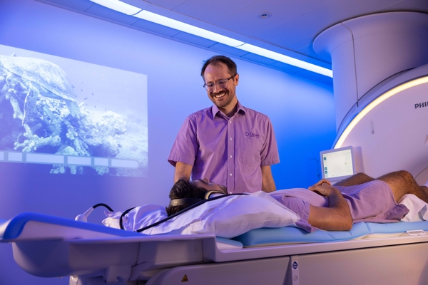 Qscan technologist putting patient through MRI machine.